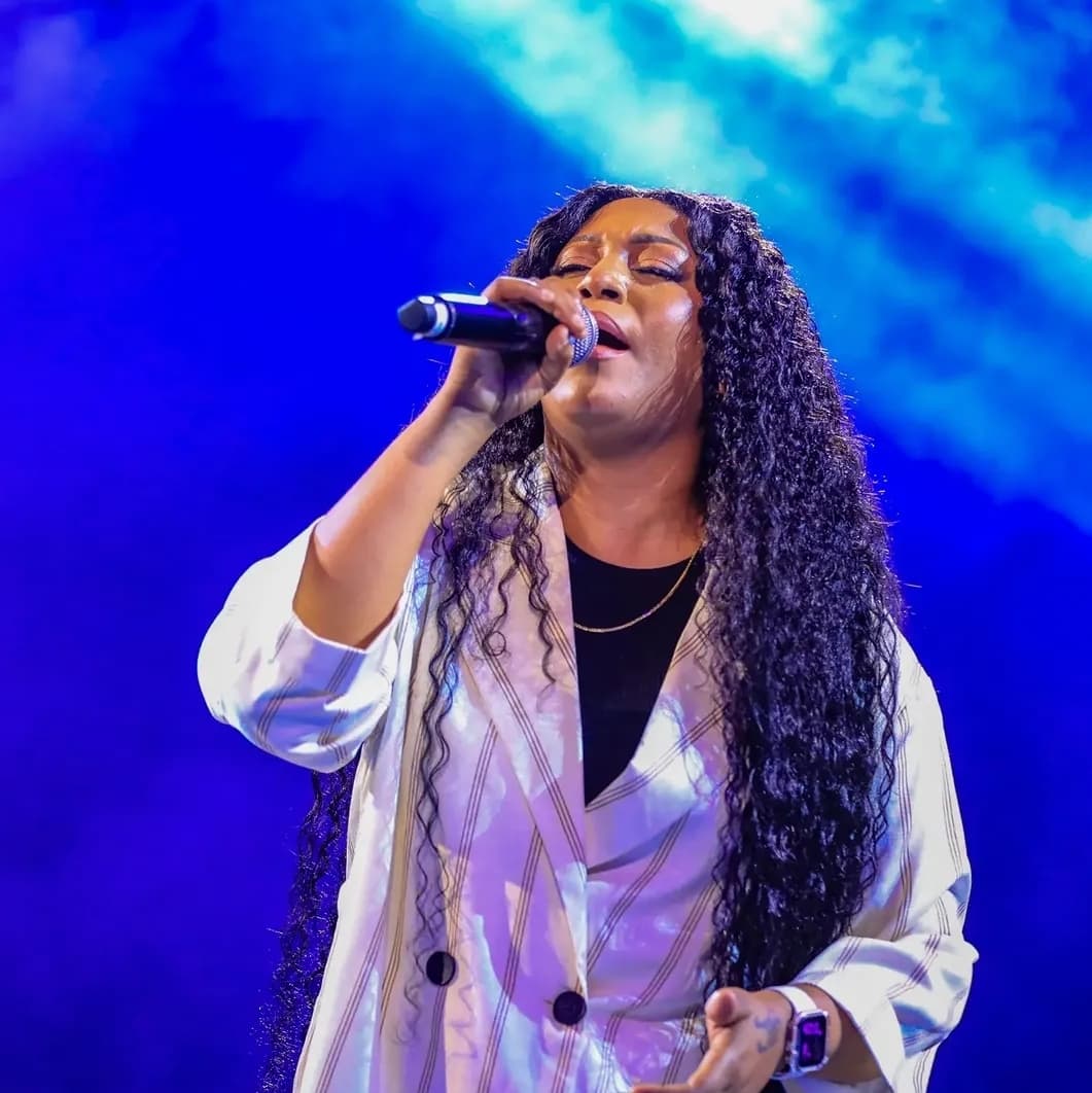 Bella Kombo singing under blue stage lighting at In Christ Now in Kigali, July 2026